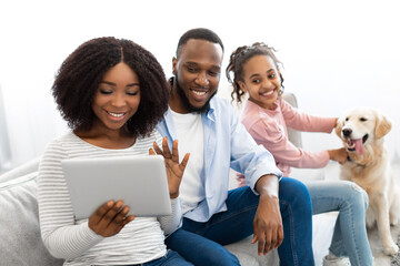 Black family having video conference using digital tablet waving hands