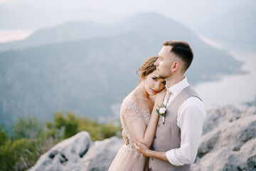 Groom embraces bride on the mountain. Portrait