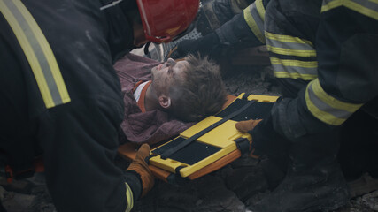 From above rescuers pulling injured teen survivor from rubble while working on remains of broken...