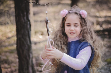 Picture of an ethnic styled little girl with long hair in a headband playing in the forest