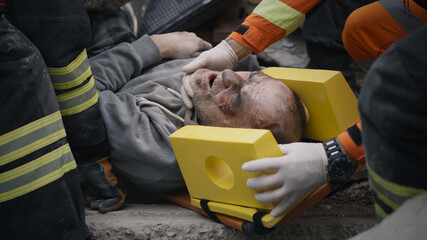 Tracking shot of crop emergency service workers lifting and carrying spinal board with injured...