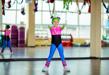 Obraz premium a small, beautiful girl,doing sports in the gym,in bright, colored sportswear