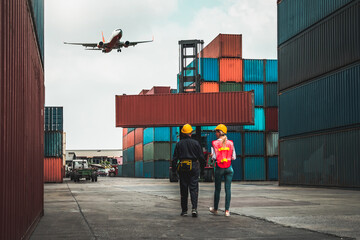 Industrial worker works with co-worker at overseas shipping container port . Logistics supply chain...