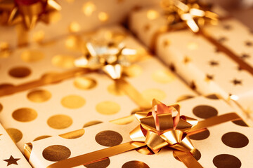 Composition of wrapped Christmas gift boxes with golden bows and ribbon. Festive decoration concept.