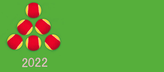 Merry Christmas, New Year concept. Greeting card, 2022 text and Orange tennis balls as a Christmas tree on green background. Top view, flat lay, banner, mock up, copy space, free text
