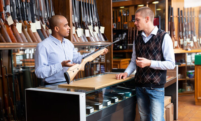 Fototapeta na wymiar Guys are choosing pneumatic rifle in gun store