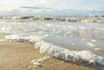 Sea foam, water surface texture, close-up. View from a sandy beach (sand dunes). Abstract natural...