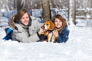 Fototapeta na wymiar Young family, couple in love on a winter walk with a beagle puppy.