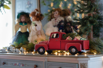 Vintage christmas toys on dresser. red toy truck and pretty dolls surrounded by soft focus white lights