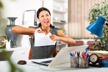 Furious asian businesswoman tearing up paper in office at workplace