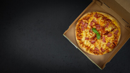 Round baked pizza in a craft box on the right against a black background