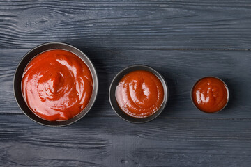 Bowls with organic tomato sauce on dark wooden background