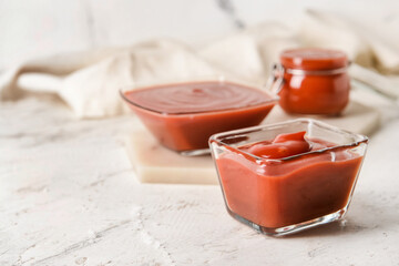 Bowl with organic tomato sauce on light background
