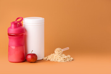 Measuring scoop with protein powder, bottle, jar and apple on color background