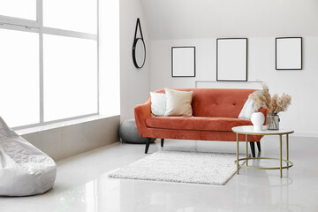 Blank posters on light wall in light living room with stylish sofa