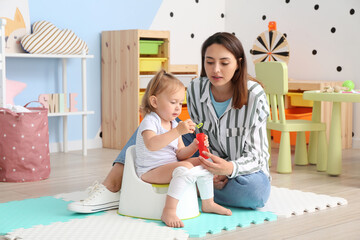 Mother potty training her little daughter at home