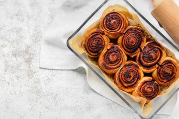 Baking dish with tasty cinnamon rolls on light background