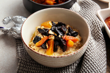Tasty sweet oatmeal with prunes, dried apricots and almond nuts in bowl on table