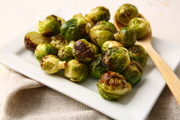Plate with tasty roasted Brussels cabbage on table, closeup