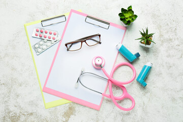 Clipboards, eyeglasses, pills, stethoscope, houseplants and asthma inhalers on light background