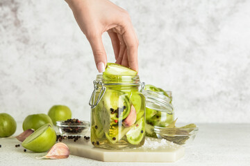 Woman canning green tomatoes on white background - obrazy, fototapety, plakaty