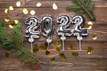 Figure 2022 made of silver balloons, fir tree branches and confetti on wooden background