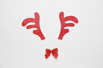 Composition with toy reindeer horns and bow on grey background