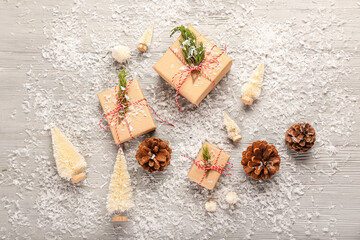 Composition with Christmas gifts, pine cones and snow on light wooden background