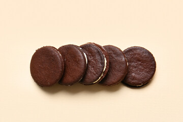 Tasty chocolate cookies with cream on beige background
