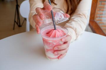Young woman, open the lid of the glass, strawberry shake out to eat inside