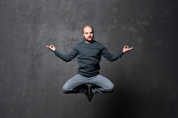 Fototapeta na wymiar Man in meditation in flight, alone at home, peaceful calm guy practicing yoga in lotus pose indoors, holding hands in mudra, freedom and serenity concept