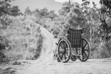 Fototapeta na wymiar Old empty wheelchair on forest trail. black and white image