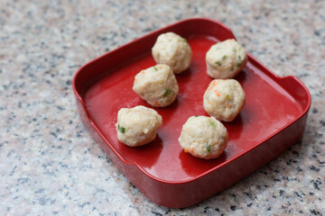 Meatballs are contained meat, flavoring and chopped vegetable which served on a red plate in Shabu or Sukiyaki restaurant.