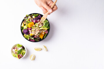 Fresh organic vegetables salad with quinoa seed in bowl and hand holding fork for eating on white background, Healthy Vegan food, Top view