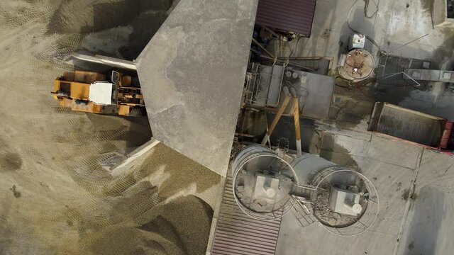 Process of concrete manufacturing with cement, water, sand and gravel at factory. Aerial top down.