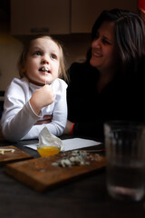 A girl eats cheese with blue mold in her mother's arms in a country house.