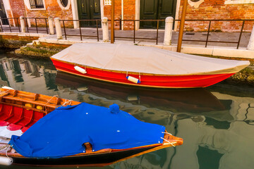 Fototapeta na wymiar Colorful small boats and side canal with reflection in Venice, Italy.