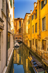 Fototapeta na wymiar Colorful small canal and boats creating beautiful reflection in Venice, Italy.