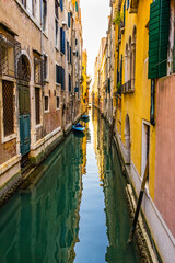 Fototapeta na wymiar Colorful small canal and boats creating beautiful reflection in Venice, Italy.