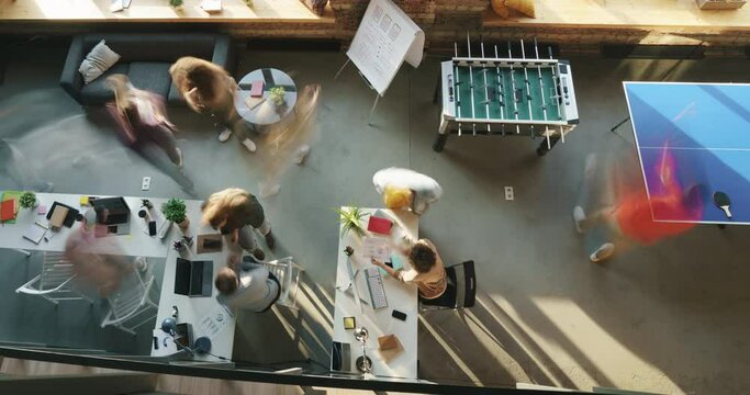 Top view time lapse of group of employees working and playing table sports in modern open space office. Business activities and teamwork concept.