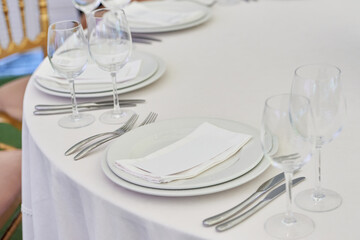 Table setting with sparkling wineglasses, plate with white napkin and cutlery on table, copy space. Place set at wedding reception. Table served for wedding banquet in restaurant