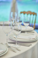 Table setting with sparkling wineglasses, plate with white napkin and cutlery on table, copy space. Place set at wedding reception. Table served for wedding banquet in restaurant