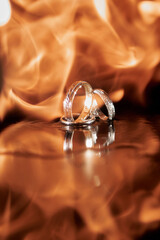 Three golden wedding rings in fire on dark background, copy space. Wedding card mock up