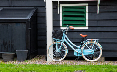Fototapeta na wymiar Europe, Netherlands, Zaanse Schans. Blue bicycle parked against dark wall.