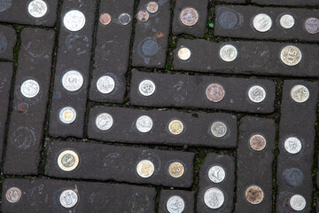 Europe, Netherlands, The Hague. World coins embedded in brick sidewalk.