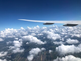 A wing tip flying through the clouds in the beautiful sky