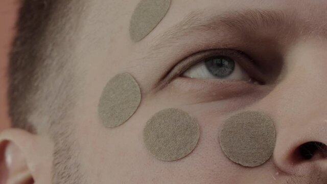 Herbal patch for the face and eyes, to improve vision, relax the muscles of the face. A man with a round herbal patch on his face. Close-up