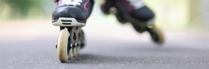 Child riding black rollerblades on road closeup
