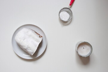 Flat lay of Christmas bread, sugar and candle against white background