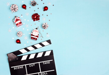 Movie clapper board with Christmas decorations on a blue background with copy space.